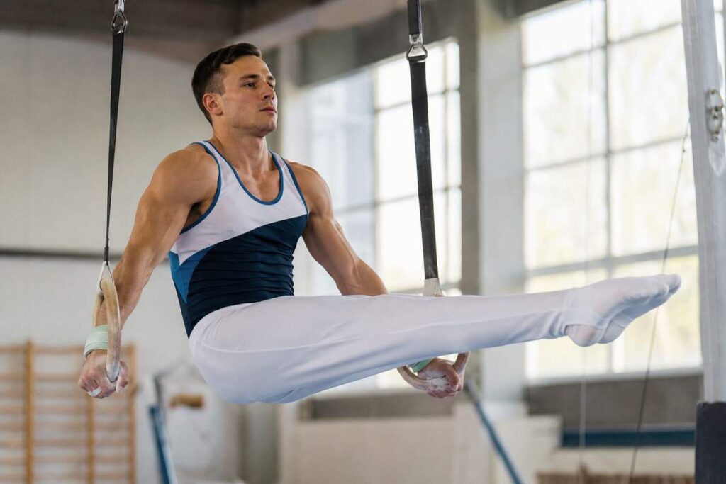 Gymnastics outfit men wear: singlet and stirrup pants on still rings