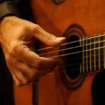 Flamenco guitarist's right hand performing the pulsamento technique near the soundhole