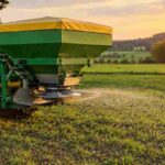 Cosmo seeder spreading fertilizer from a tractor in a green field