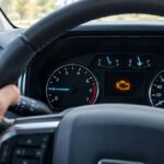 Ford check engine light glowing amber on the instrument cluster while a driver holds the steering wheel