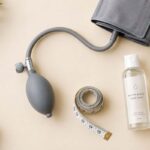 Inflatable dildo pump, tape measure, and water-based lubricant on a flat lay